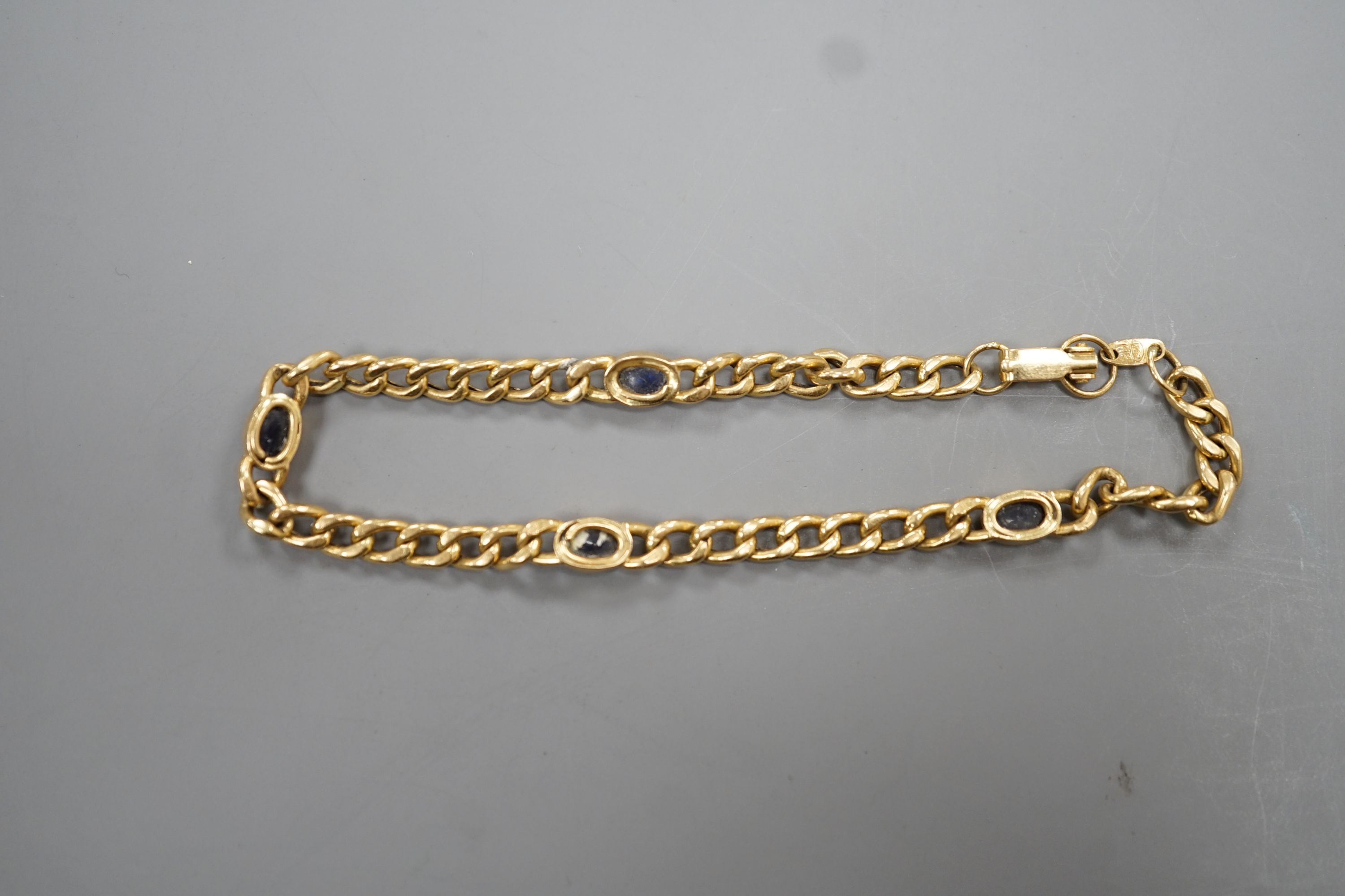 A yellow metal and blue cabochon stone set curb link bracelet, 18cm, gross weight 9 grams.